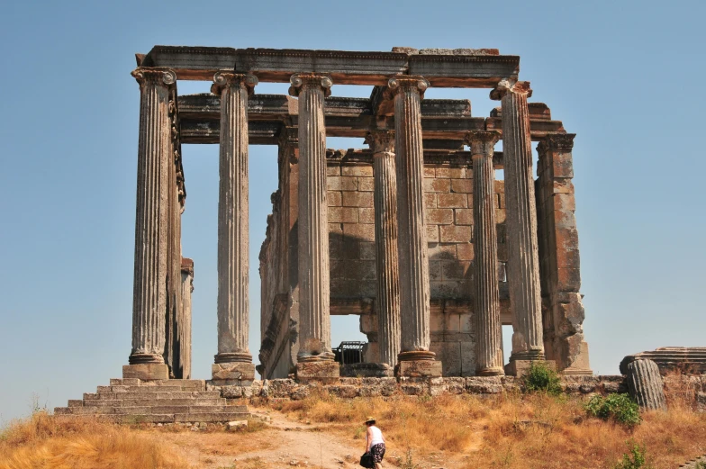 a young man is walking down a path in front of ancient ruins