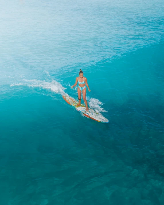 a woman riding a surfboard in the middle of an ocean