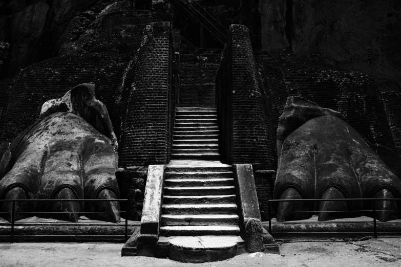 three statues and staircases near two mountains