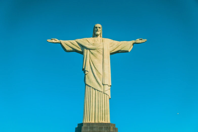 the christ of jesus statue at the base of a tall, white statue on a clear day