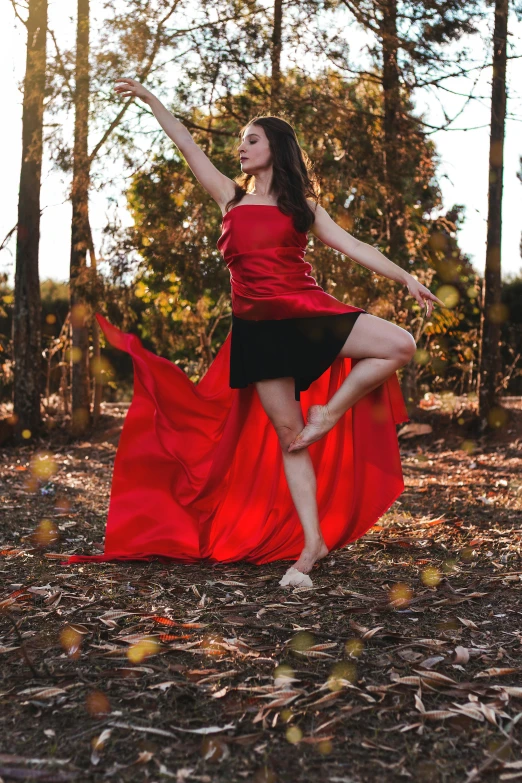 a beautiful woman in a red dress posing in the woods