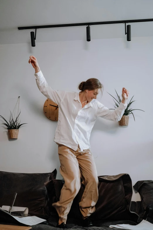 a woman is dancing in the room near a black couch