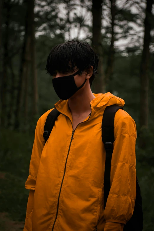 a young man wearing an orange raincoat and a black mask