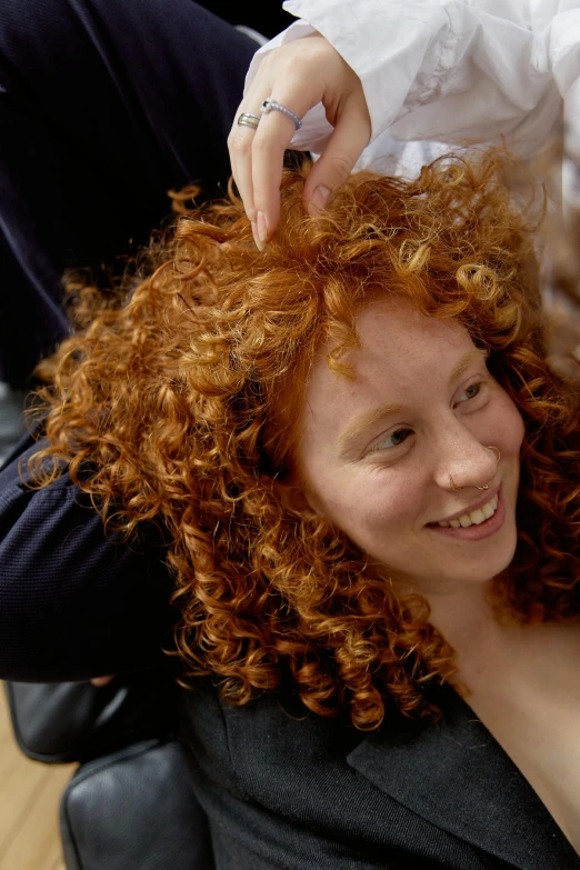 a woman getting her hair styled and wearing an evening dress