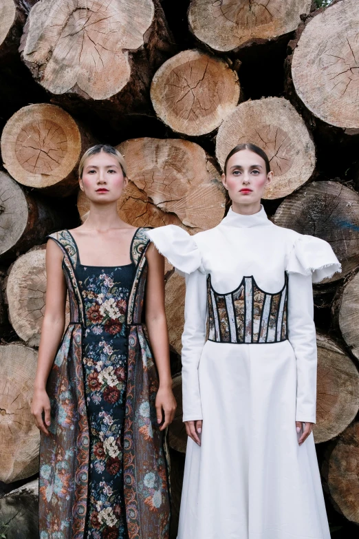 a picture of two girls standing in front of logs