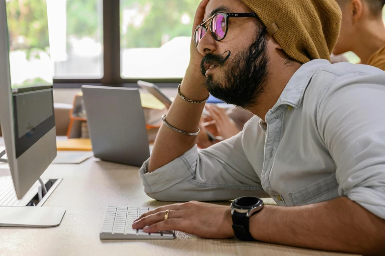 a man sitting in front of a computer wearing glasses