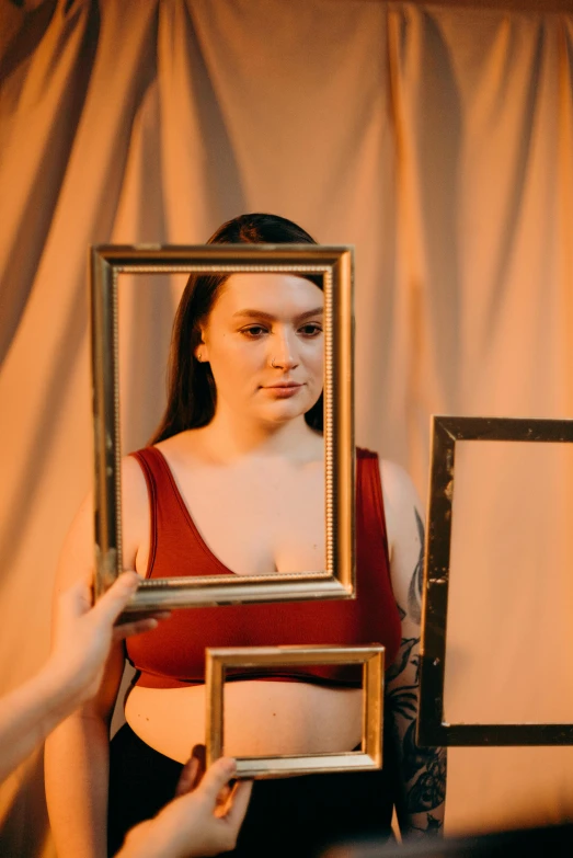 a woman in red shirt looking in a po frame