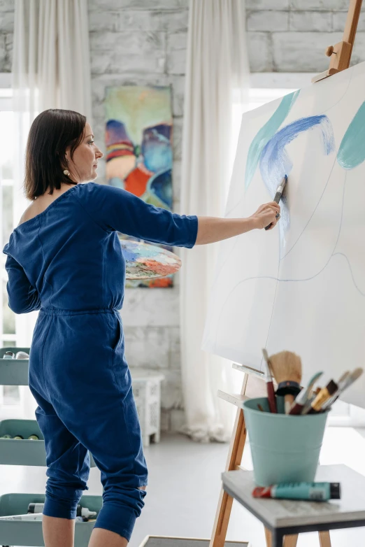 a woman at a easel in front of a painting on a whiteboard