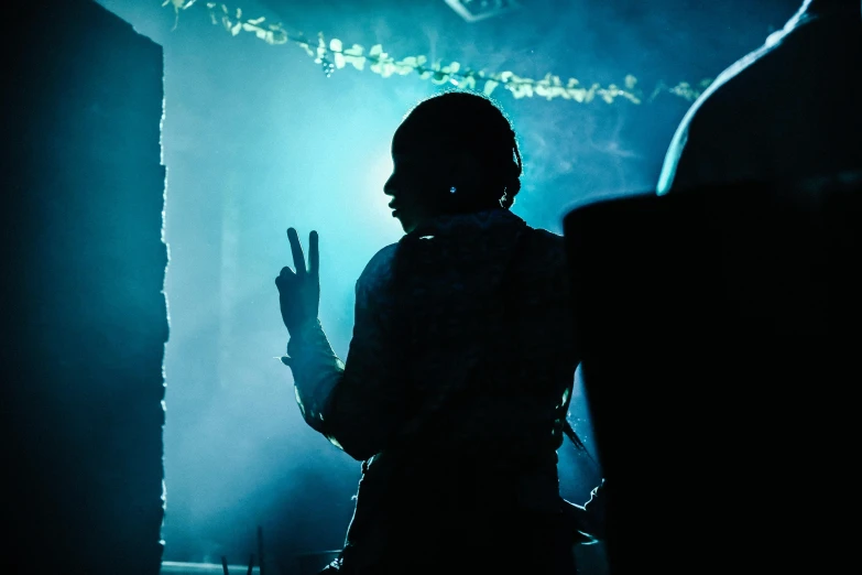 the silhouette of the person standing in front of a dimly lit room