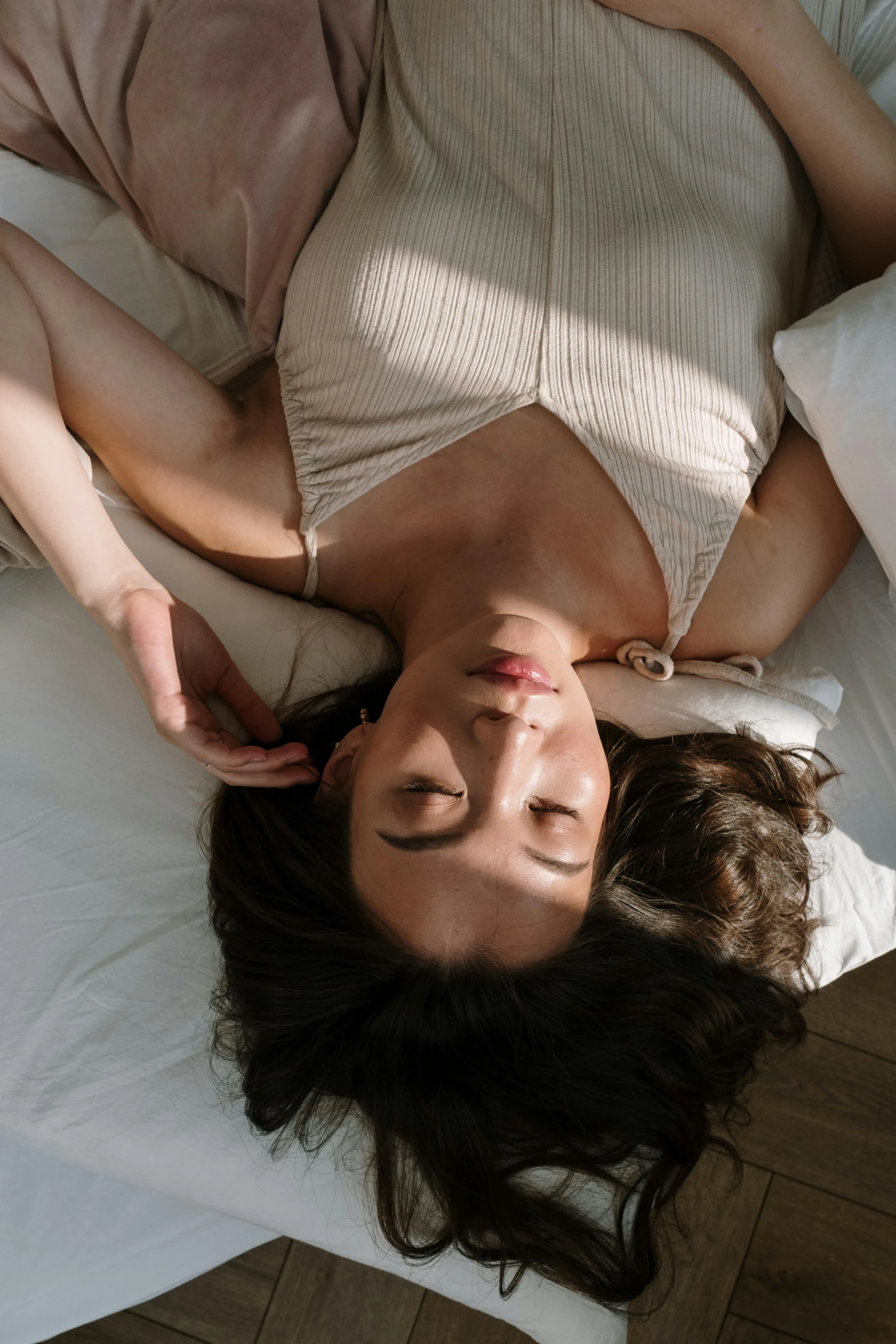 an aerial view of a woman in a white top lying on a bed