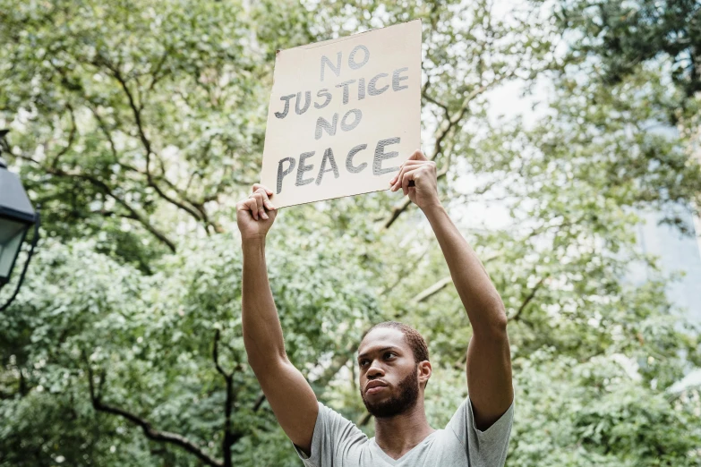 a man holding up a sign that says no justice and peace