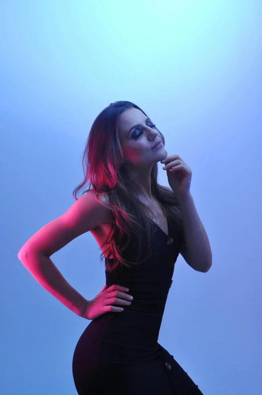 a girl posing against a blue wall while talking on her cell phone