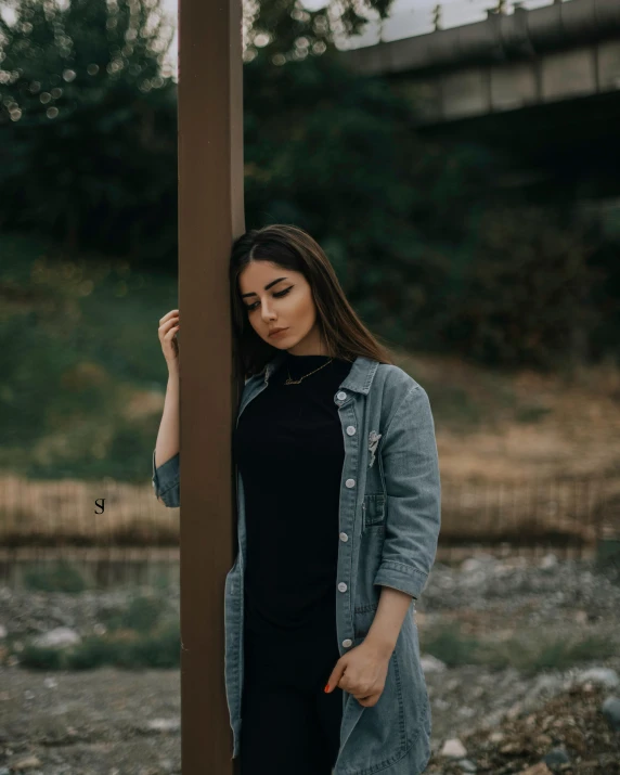 a woman leaning against the pole in the middle of nowhere