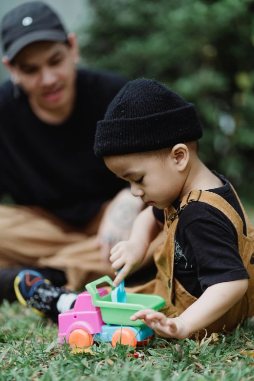 a man helps a small boy use a toy truck