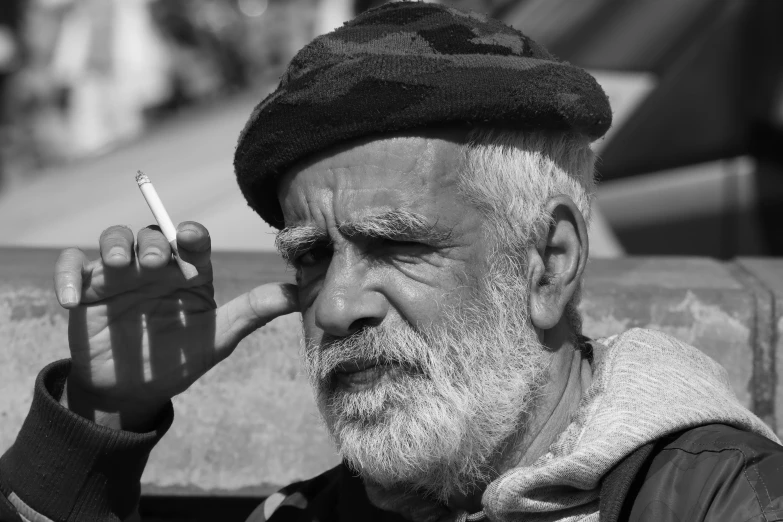 an elderly man sitting on a couch smokes a cigarette