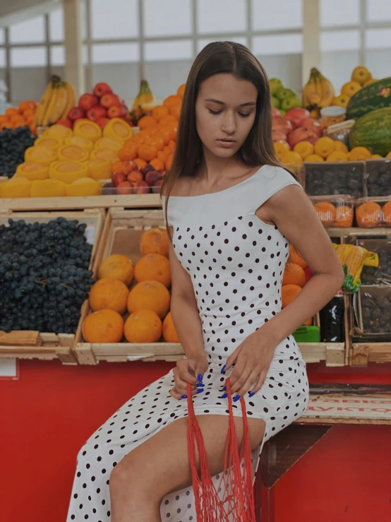 a girl sitting on the fruit stand in front of her purse