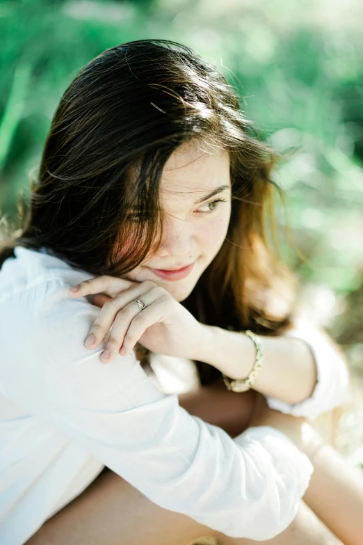 a girl sitting on the ground with her hand on her cheek