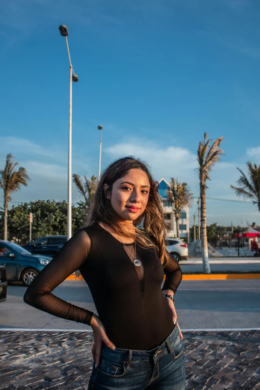 a beautiful young woman posing in front of a palm tree