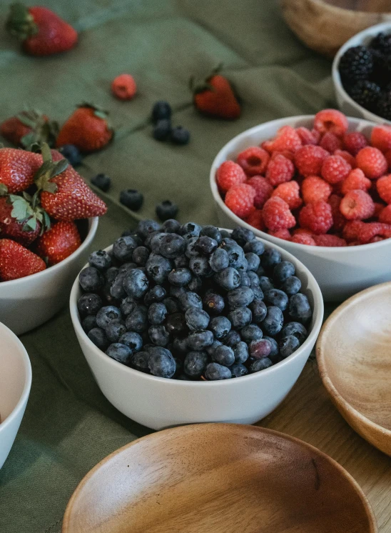 bowls of berries and strawberries sit in front of bowls of other fruits