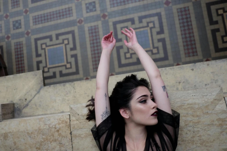 a woman in sheer clothes sitting on a ledge