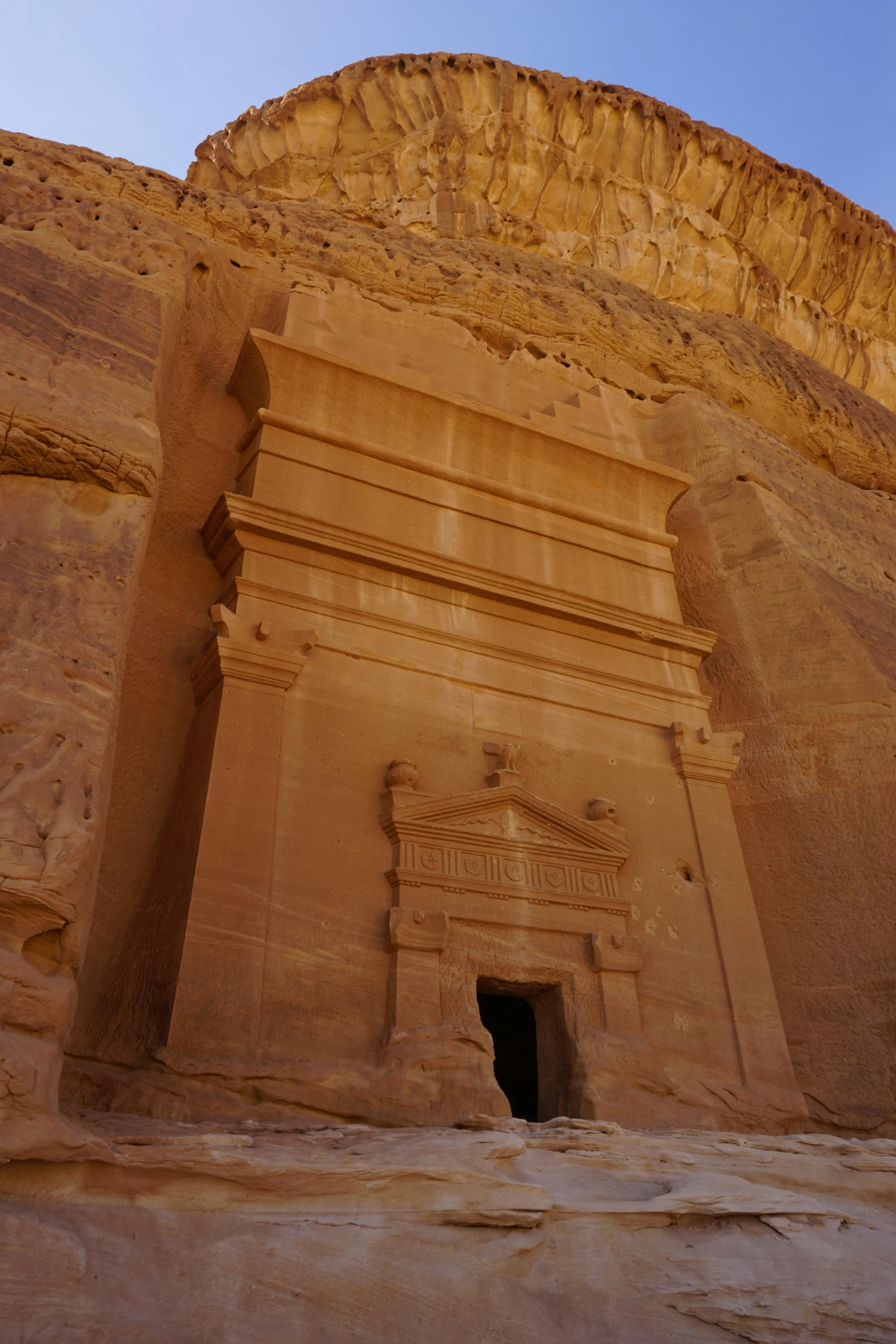 an elaborate doorway in the side of a cliff, near a body of water