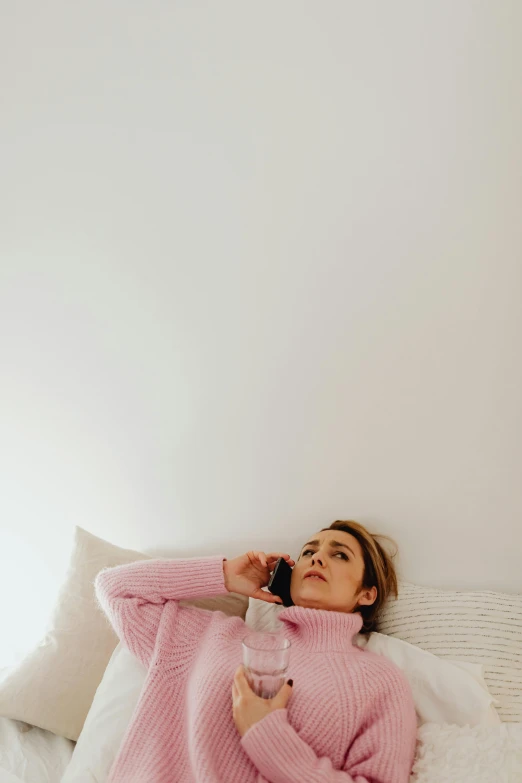 a woman laying down in bed talking on a phone