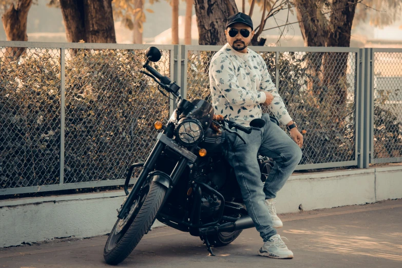 man wearing hat and sunglasses posing with his motorcycle