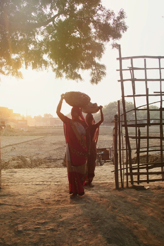 woman in a colorful sari and hat walking up stairs to a cage with a large tree