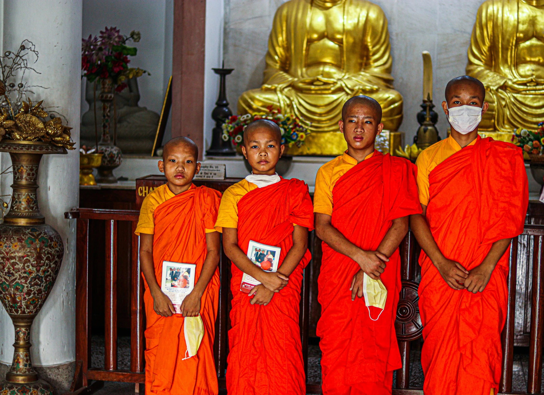 four monks in orange garb pose for the camera