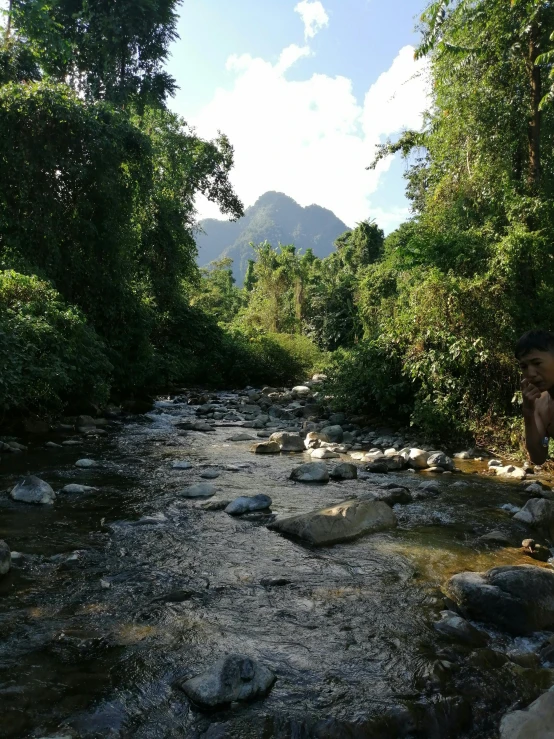 a young person crouched down to look at a small stream