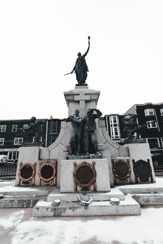 a statue in a snowy park surrounded by buildings