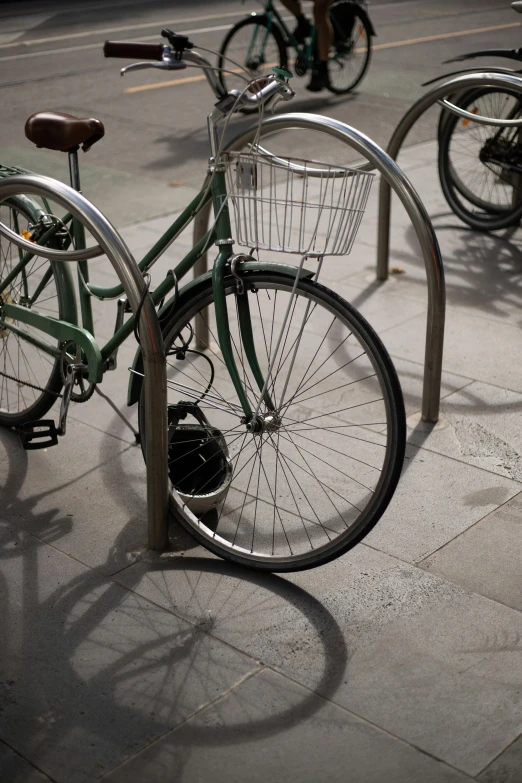 a green bike parked next to a metal rack