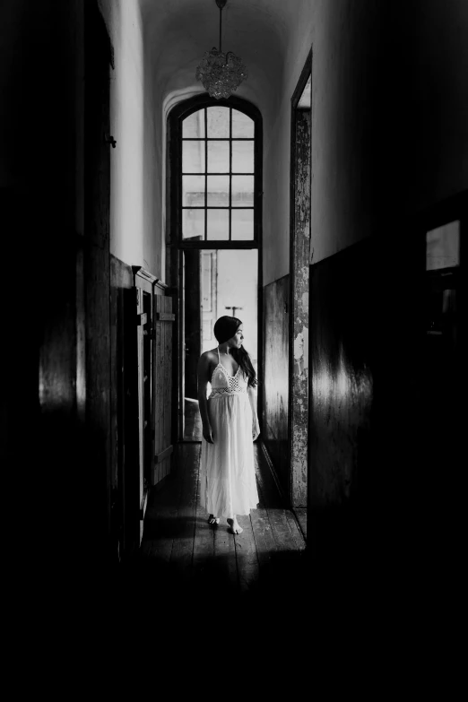 a woman wearing a dress walking down a hall