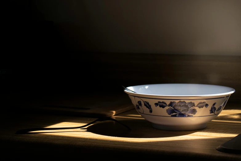 a blue and white bowl with flowers sits on the floor