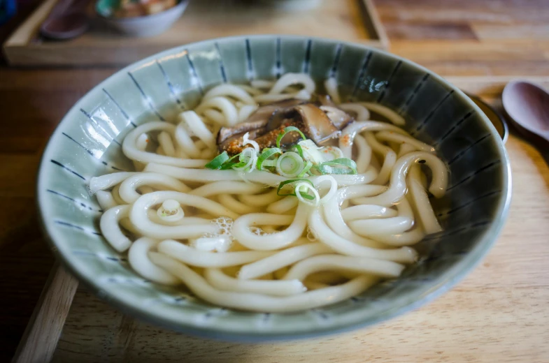 noodles are topped with mushrooms and a sprig of mint in a blue bowl