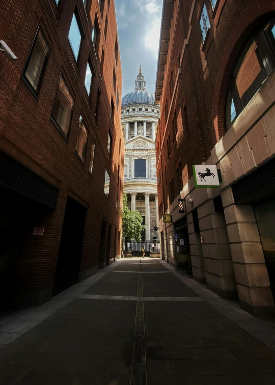 a narrow alley between two large building with a large steeple