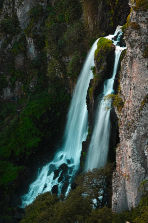 a very long waterfall in the middle of some rocks