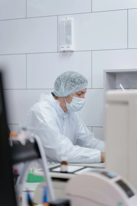 the nurse is working on his computer wearing a mask