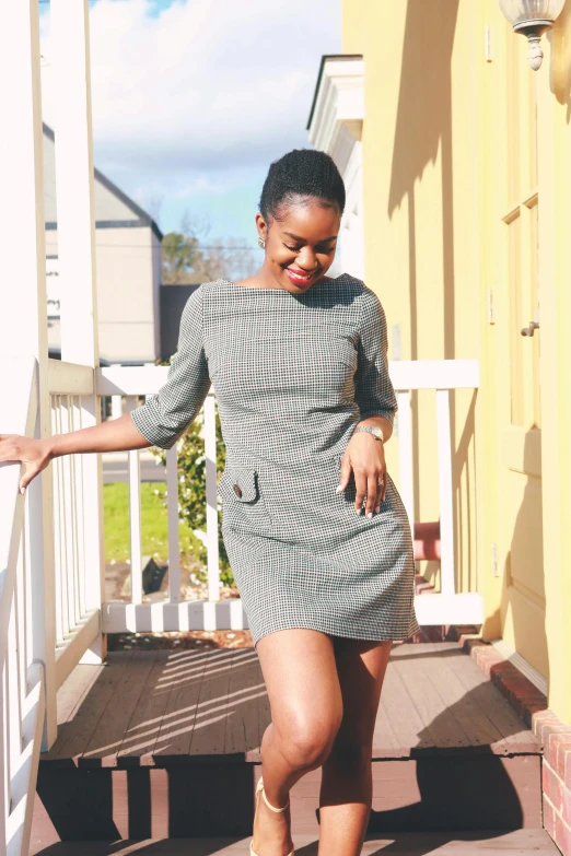 a black woman standing on a porch with her arms behind her back