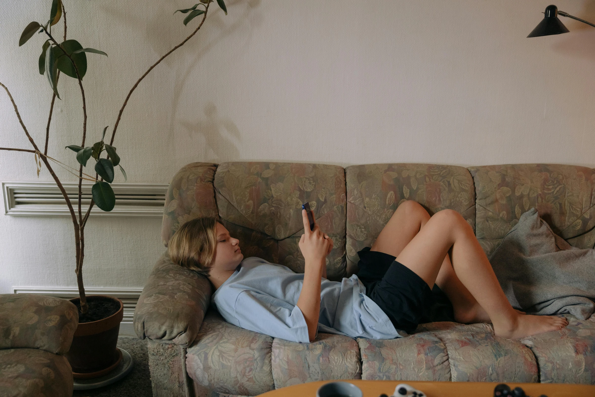 a woman is laying on a couch in a living room while looking at her phone