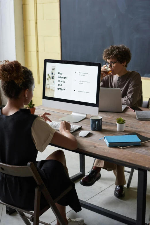 a couple of people sitting at a table with two laptops