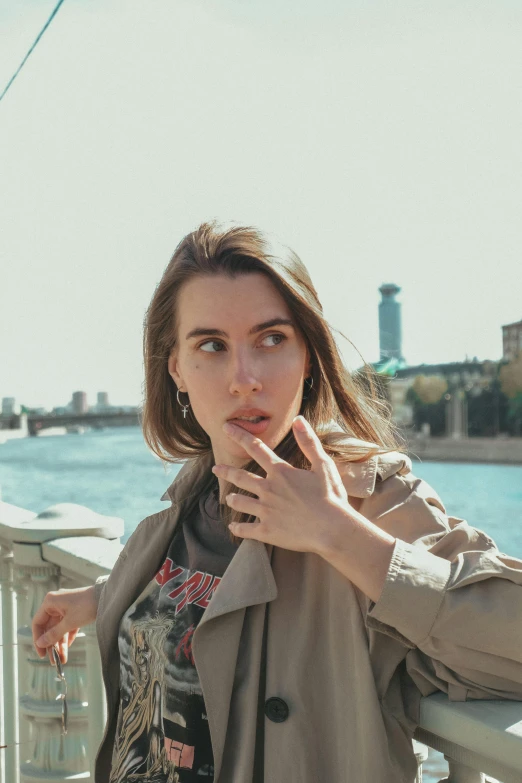 a woman standing by a railing wearing a jacket and smoking a cigarette