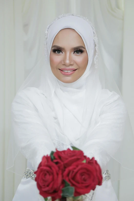 a woman in a veil holds a rose bouquet in her hand