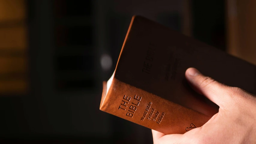 a hand holding a bible while it is not opened