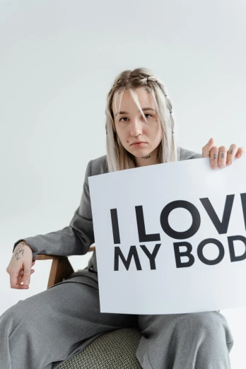 a woman holding up a sign that says i love my body