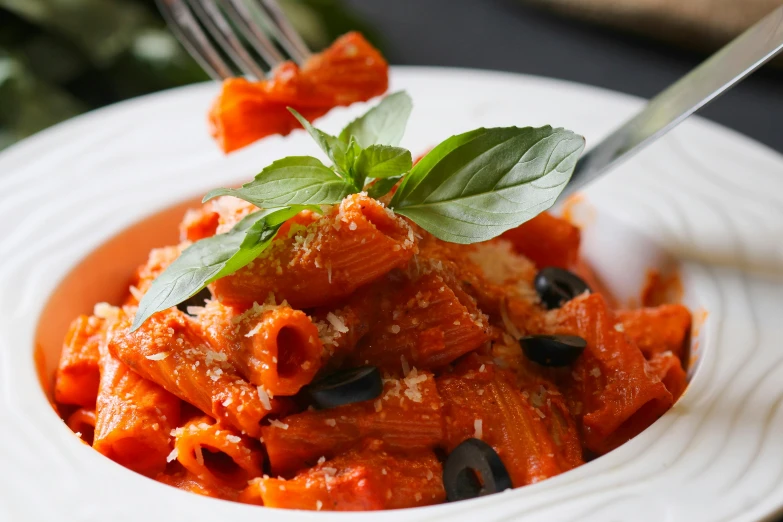 a plate of pasta with sauce, cheese and olives