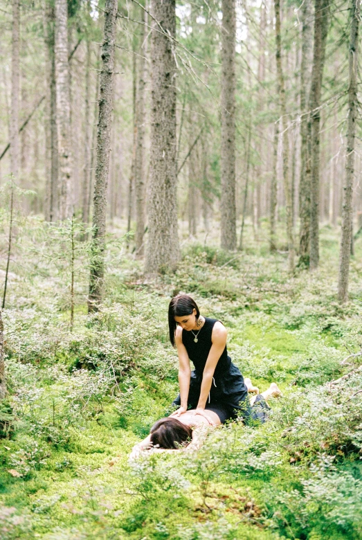 woman kneeling down in the middle of a forest with her head resting on a dog