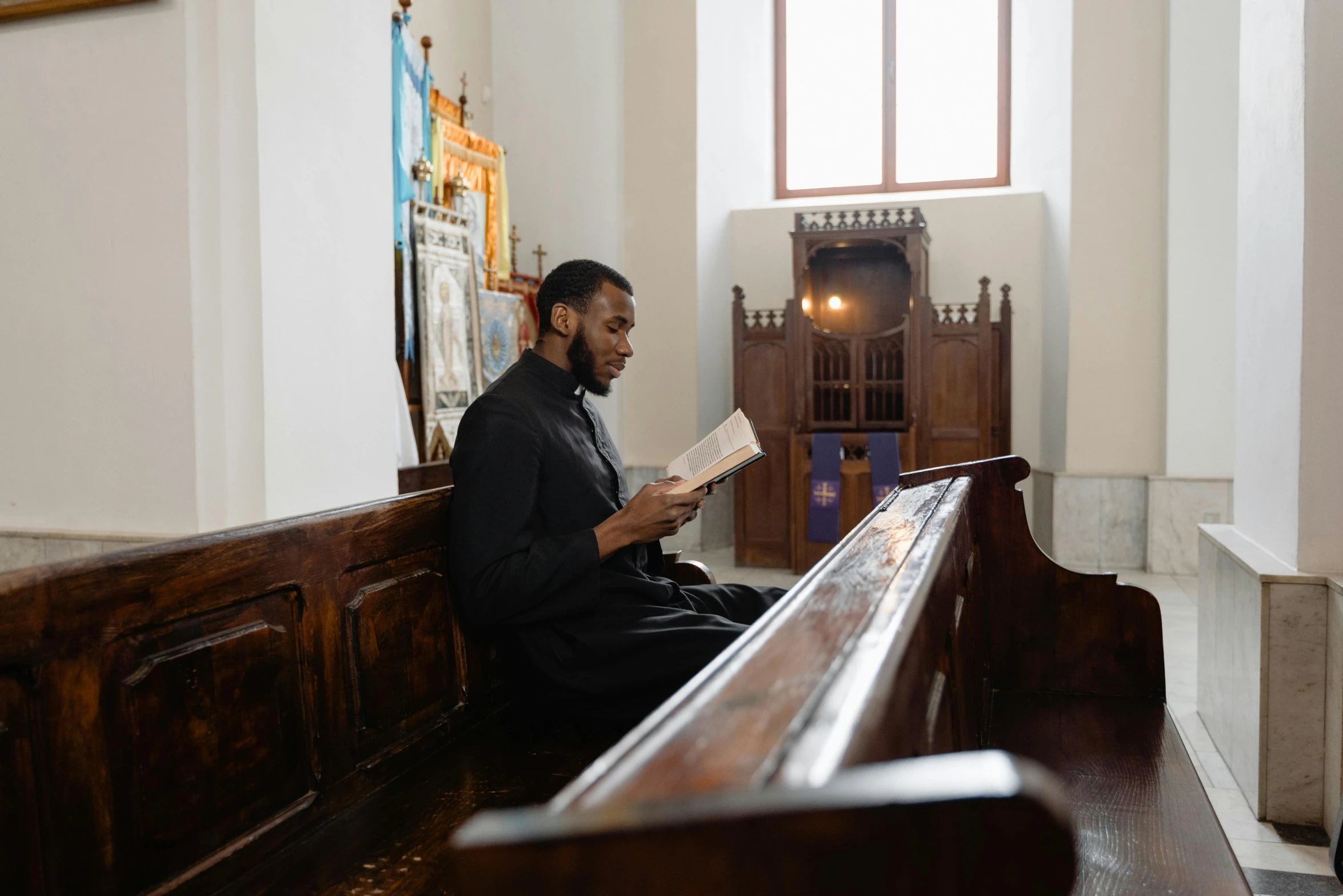 a man sitting on a church pew reading