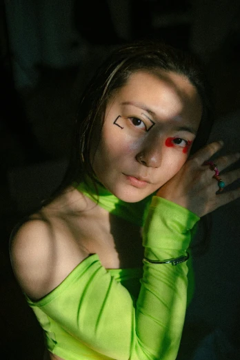 a young woman with dark makeup, wearing green