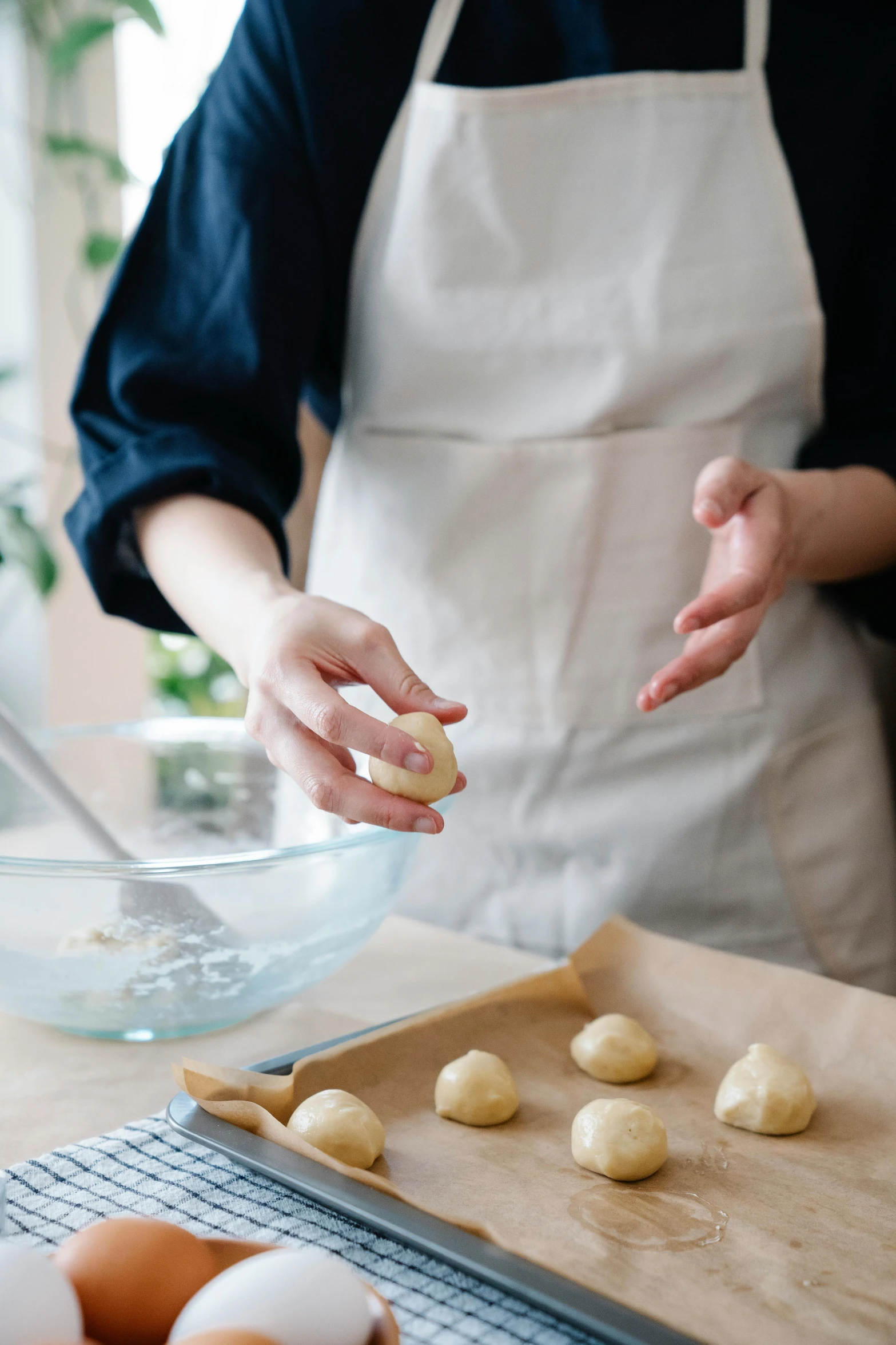 a woman is making dough balls on a board